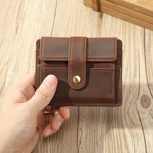 Brown leather wallet held by a hand on a wooden surface